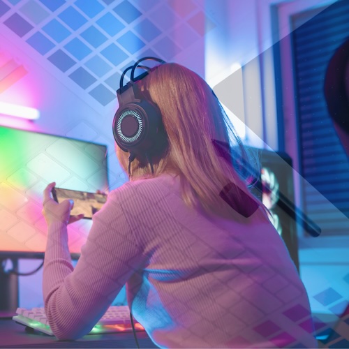 girl in front of a computer with a colorful background wearing headphones and holding her phone in landscape orientation while playing a game