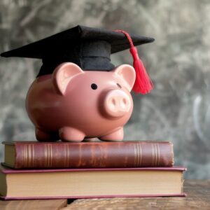 Smart Bundle - A pink piggy bank wearing a graduation cap sits on top of two closed books, symbolizing education and financial savings on a simple wooden table surface.