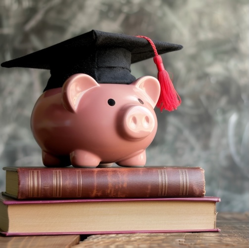 Smart Bundle - A pink piggy bank wearing a graduation cap sits on top of two closed books, symbolizing education and financial savings on a simple wooden table surface.